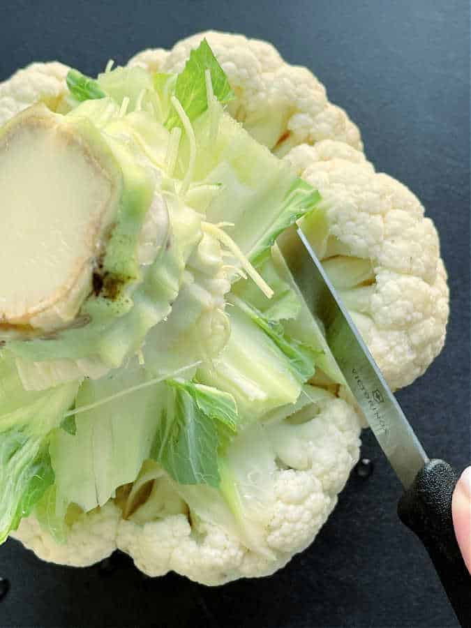 whole head of cauliflower on a cutting board ready to be cut into florets