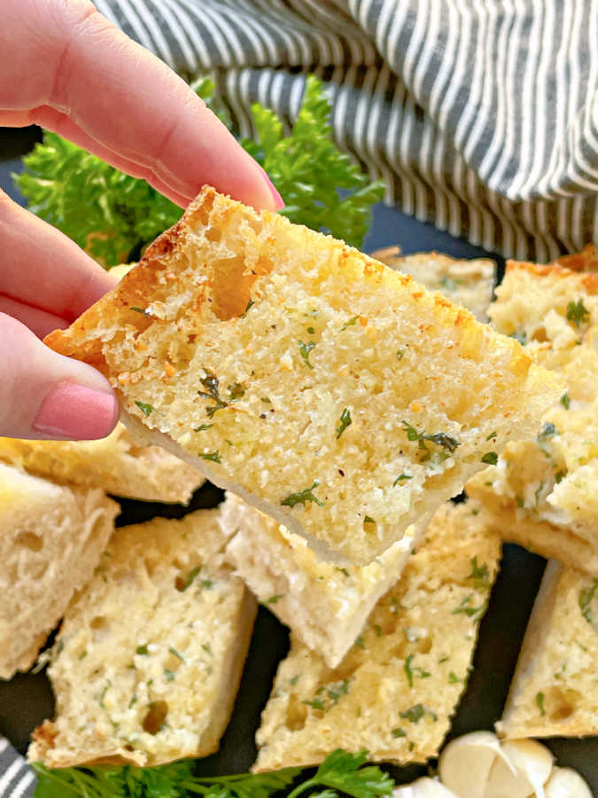 taking a bite of a slice of air fryer garlic bread