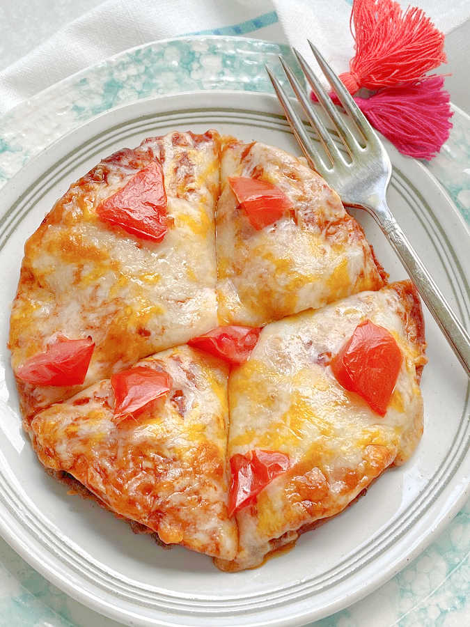 showing a whole air fryer mexican pizza, sliced, on a plate