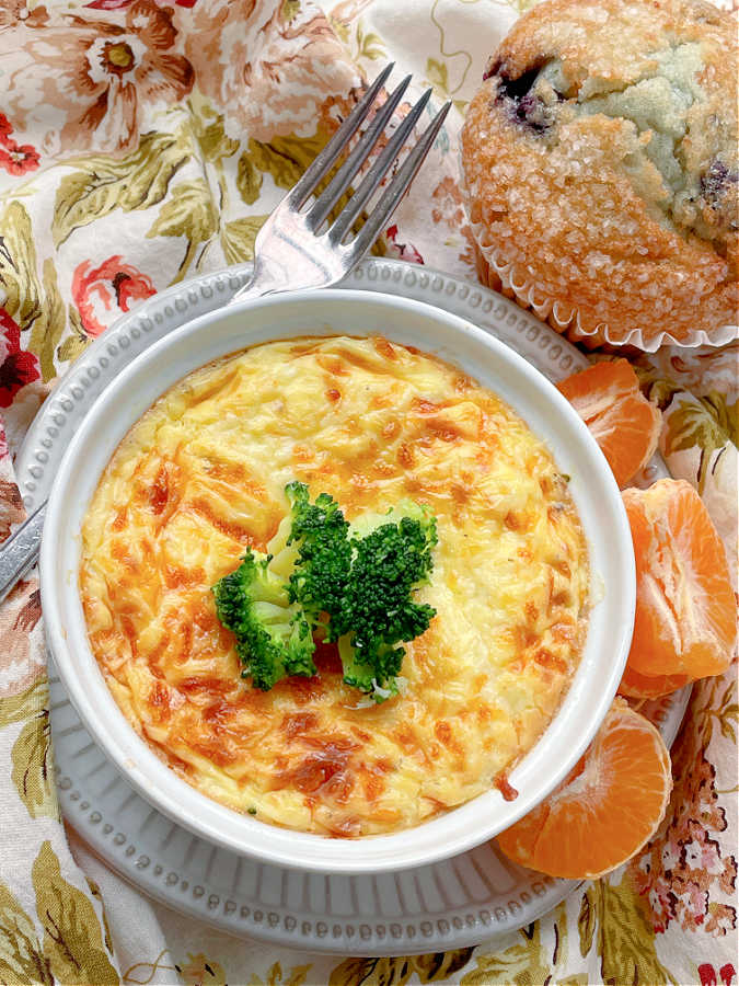 air fryer quiche pictured with orange sections and a blueberry muffin on the side