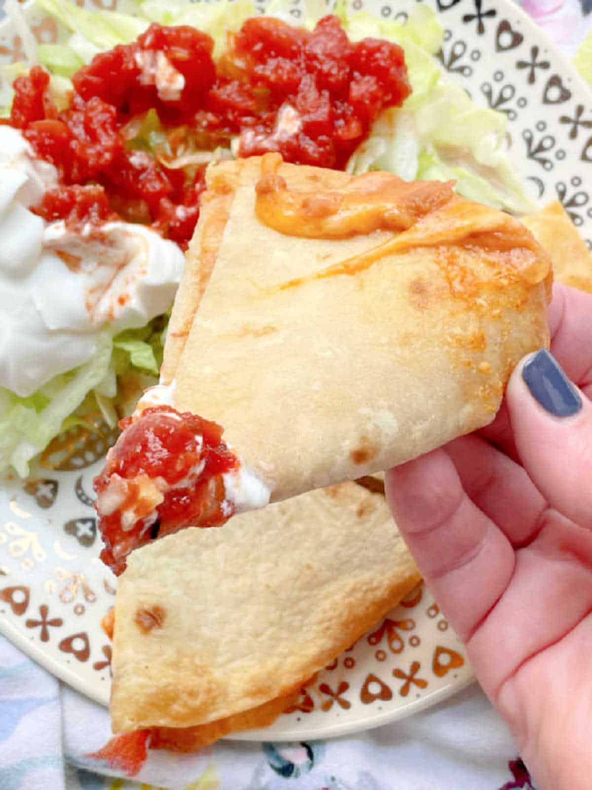 dipping a slice of cheesy quesadilla into tomato salsa