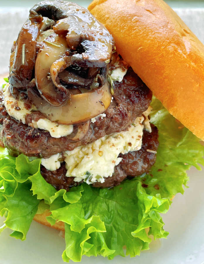 side view of a stacked wagyu burger topped with mushrooms and Boursin cheese