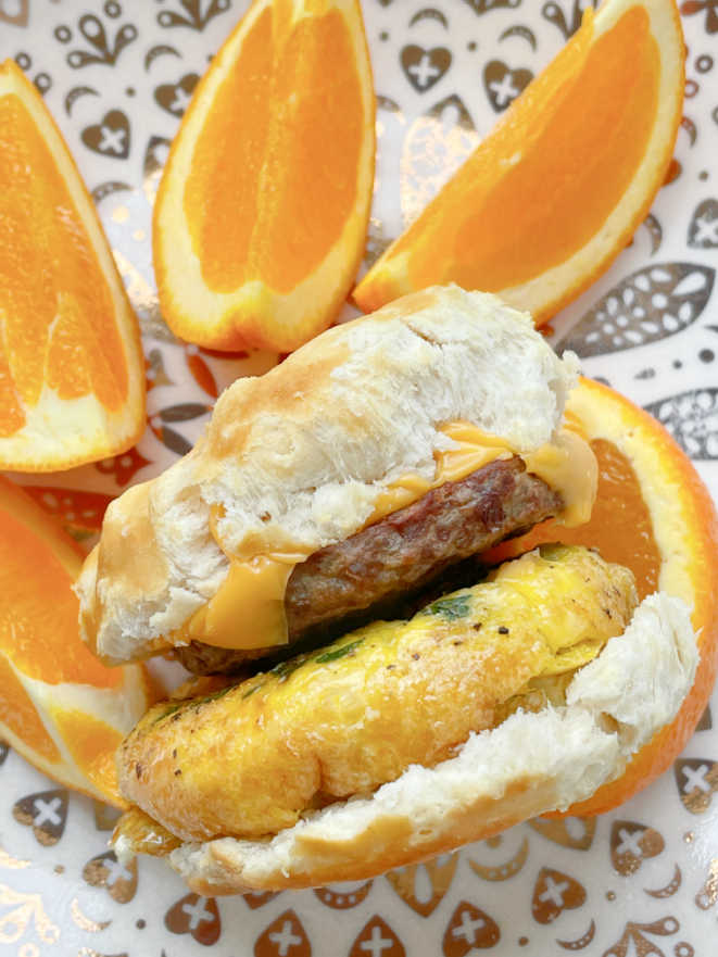 air fryer breakfast sandwich on a plate with orange slices