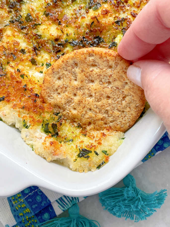 dipping a cracker into baked lobster al forno