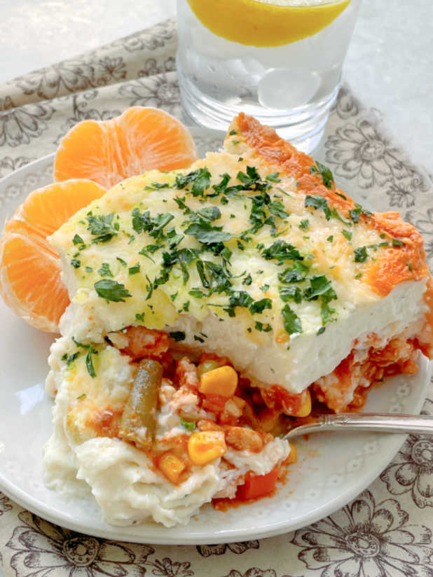 showing a slice of healthy shepherd's pie on a plate with orange slices