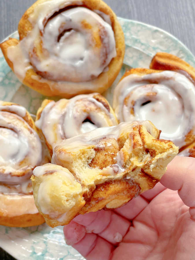 taking a bite of an air fryer cinnamon roll