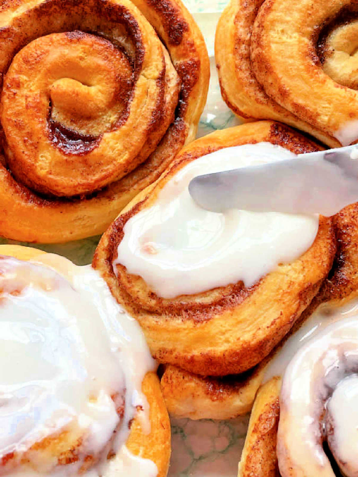 frosting the warm cinnamon rolls