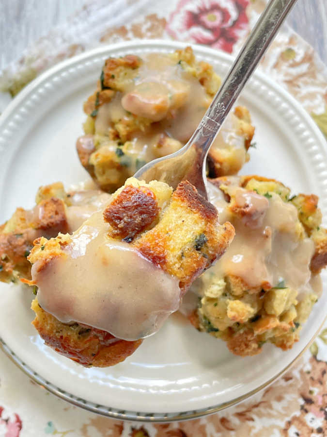 taking a bite of a stuffing muffin topped with gravy