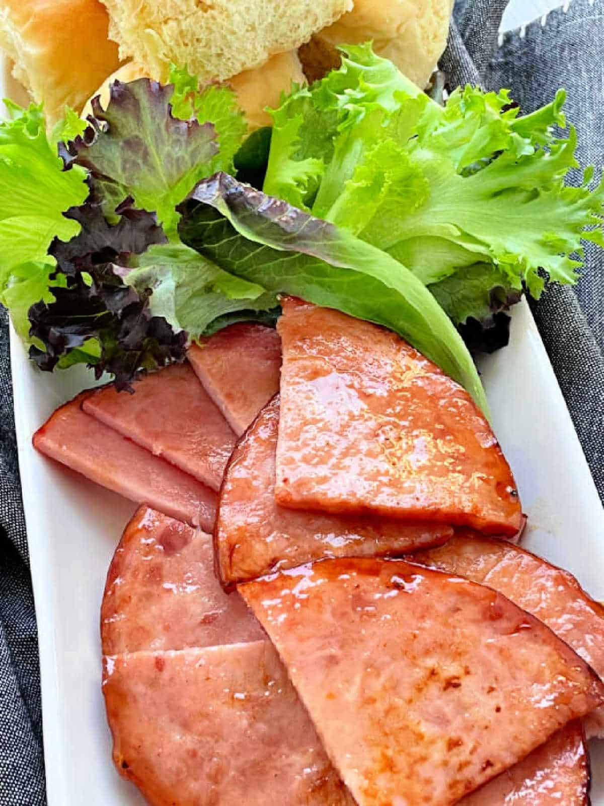 air fryer ham steaks on a platter with slider buns and lettuce