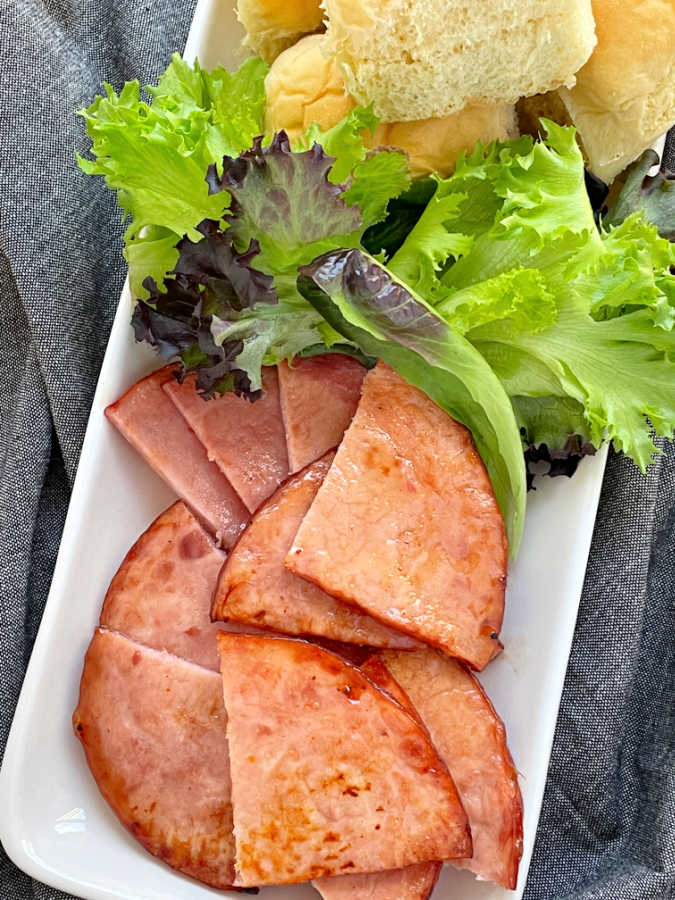 air fryer ham steaks on a platter with lettuce and sandwich rolls