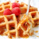 churro waffle drizzled with caramel sauce and garnished with fresh raspberries