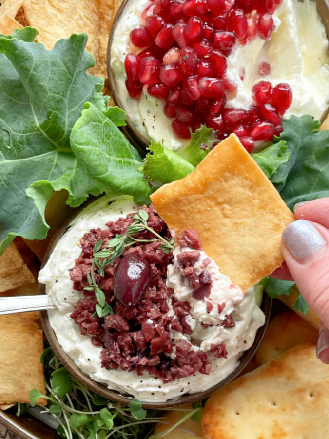 dipping a pita chip into savory greek feta dip