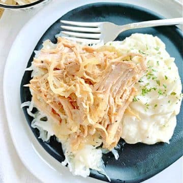 pork and sauerkraut plated with a side of mashed potatoes