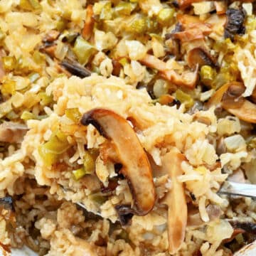 serving a spoonful of mushroom rice pilaf from the casserole dish