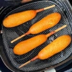 four corn dogs freshly fried in the air fryer basket
