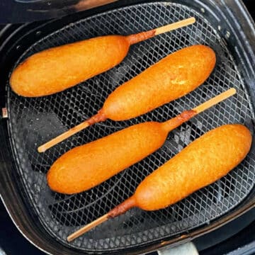 four corn dogs freshly fried in the air fryer basket