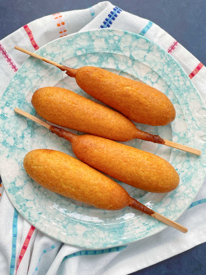 four air fryer corn dogs plated on top of a striped towel