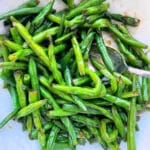 a pile of air fryer green beans with soy sauce glaze in a white bowl