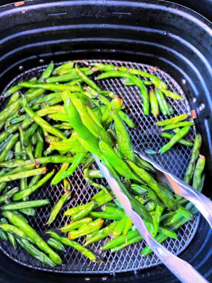 Learn how to quickly roast frozen or fresh green beans to perfection in your air fryer. They are finished with a soy sauce glaze.