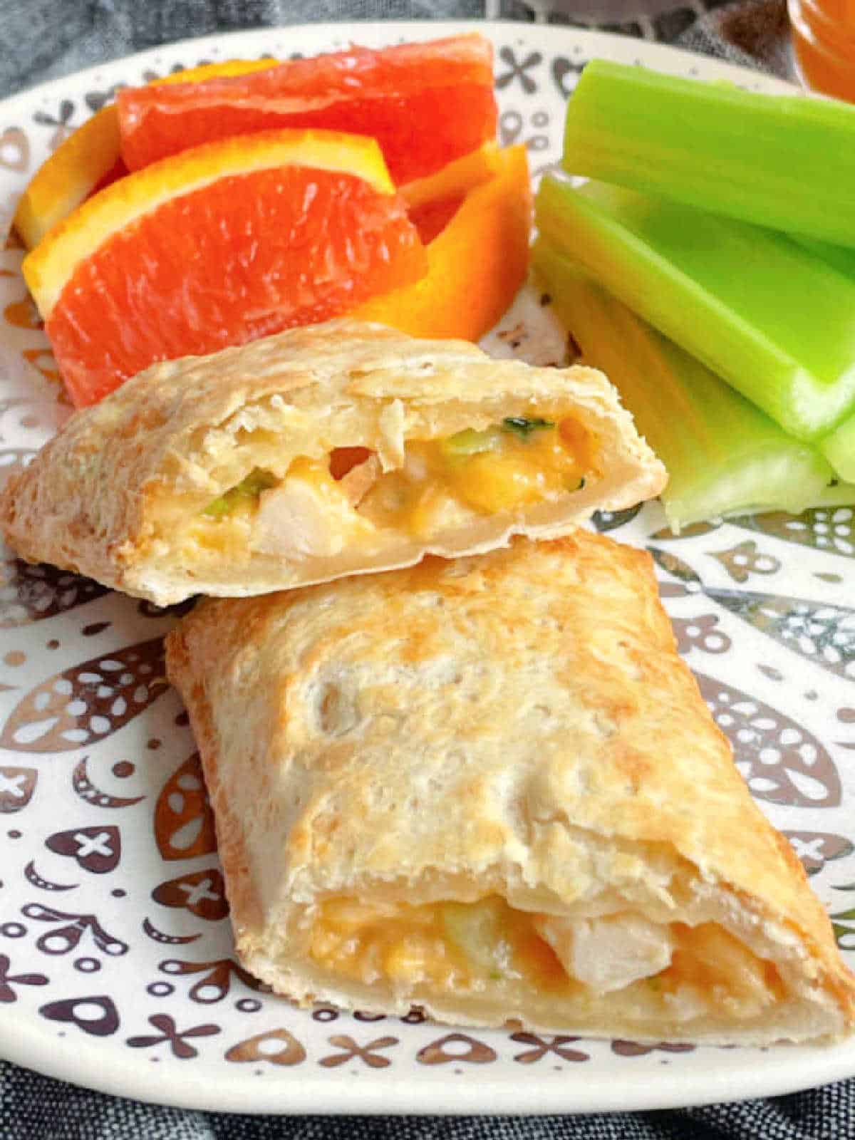 an air fryer hot pocket sliced in half and plated with celery and orange slices