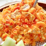 plated buffalo chicken mac and cheese drizzled with hot sauce