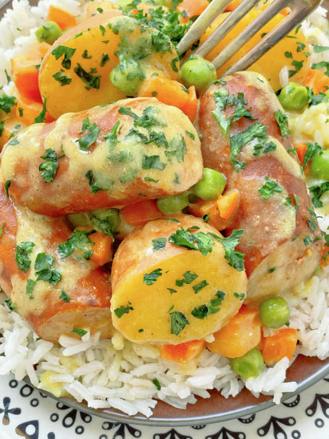 slow cooker curried sausage and potatoes on a plate served over rice