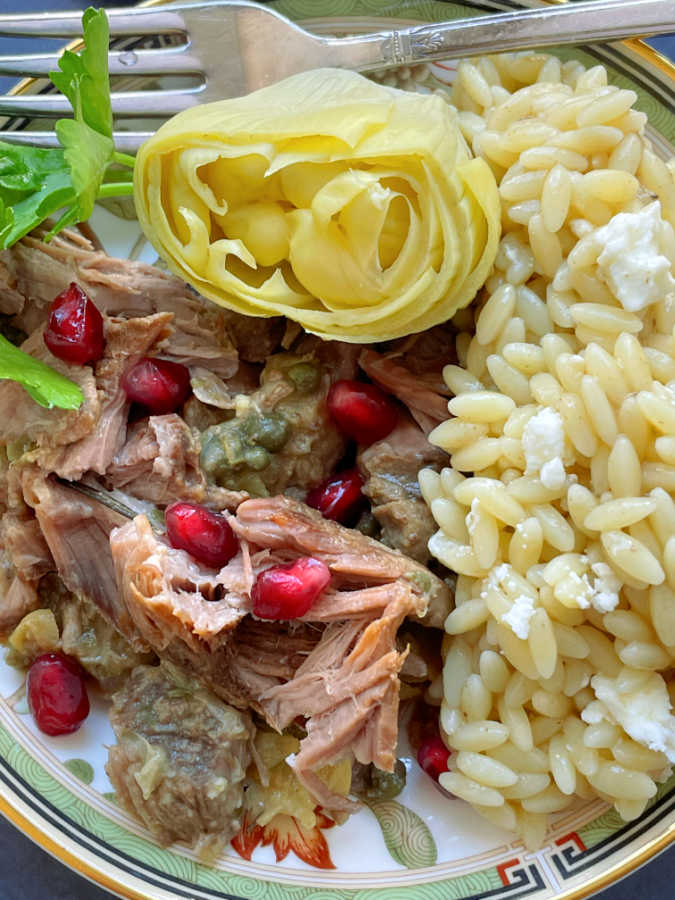 slow cooker lamb shoulder plated with a whole artichoke heart and orzo pasta