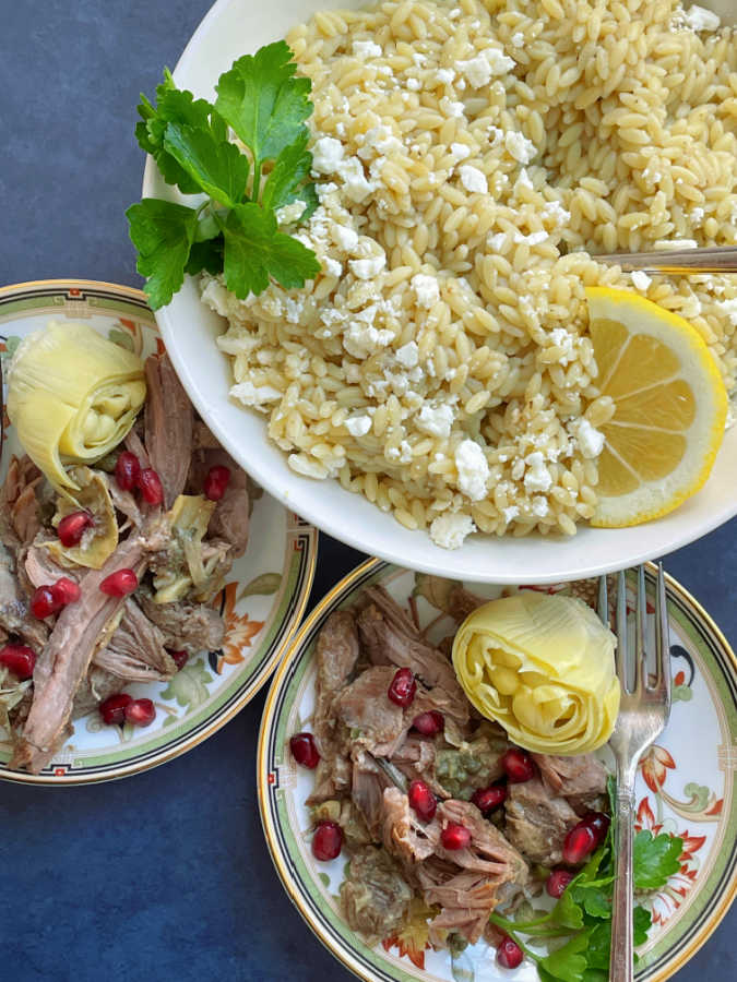 slow cooker lamb shoulder plated individually with a side dish of orzo pasta topped with feta cheese