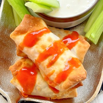 air fryer buffalo chicken egg rolls on a platter with celery and blue cheese dressing