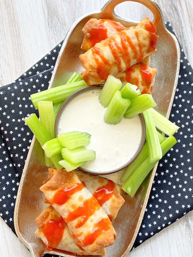 air fryer buffalo chicken egg rolls on a platter with cut celery and blue cheese dressing