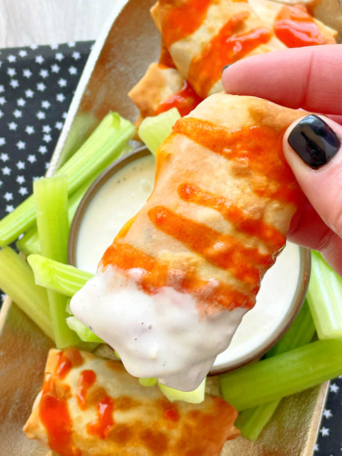 dipping a buffalo chicken egg roll into blue cheese dressing