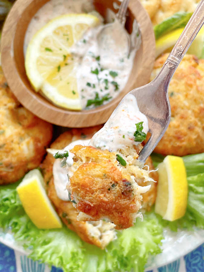 taking a bite of air fryer crab cake after being dipped in lemon mayonnaise sauce