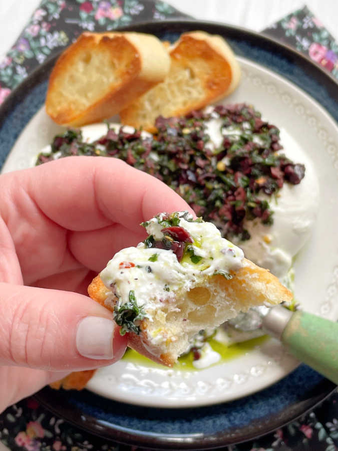 taking a bite out of a piece of burrata bruschetta