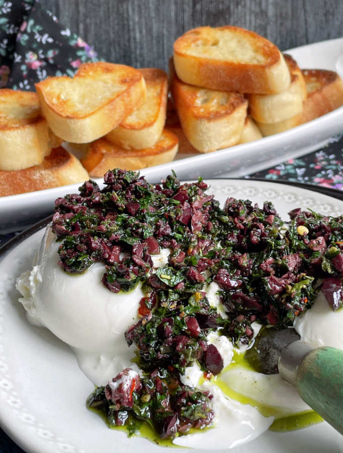 plated burrata bruschetta with baguette slices in the background