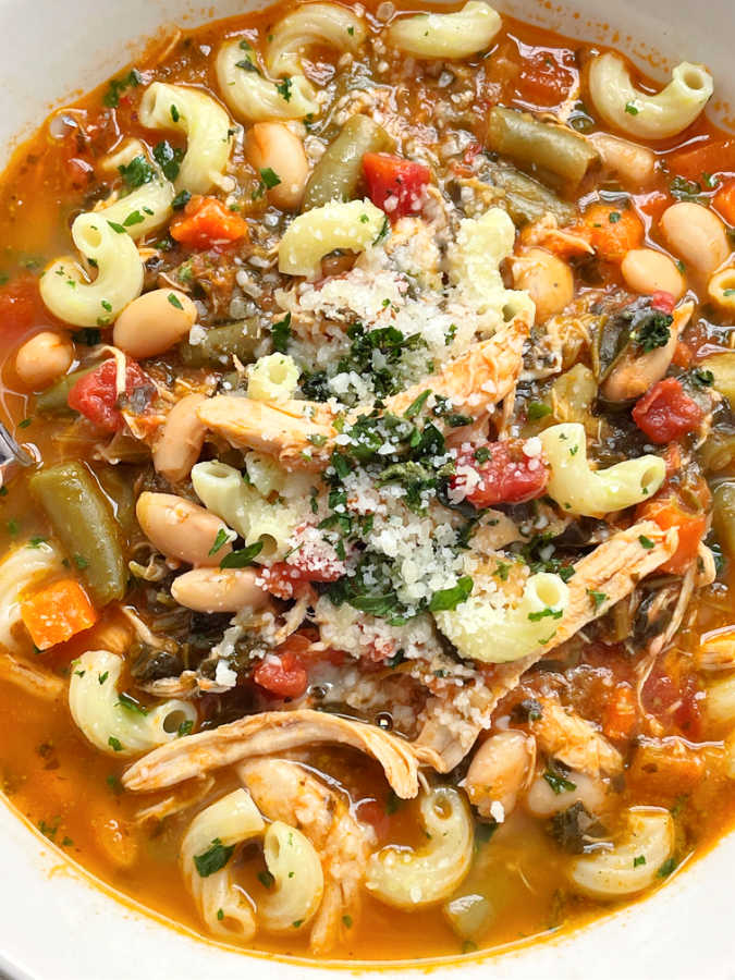 close up view of chicken minestrone soup topped with parmesan cheese