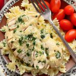 crock pot ranch chicken plated over pasta with a side of tomatoes