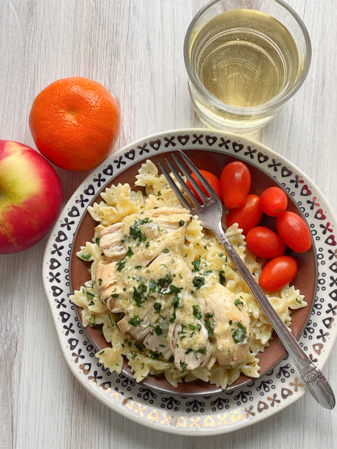 crock pot ranch chicken plated with a glass of wine and apple on the side