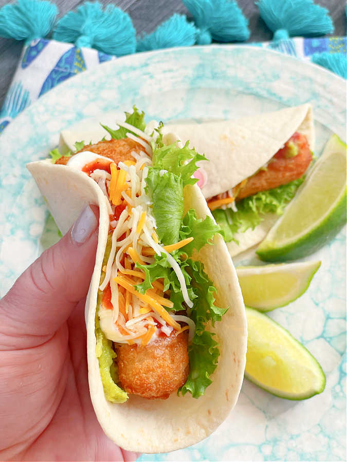 taking a bite of an air fryer frozen fish taco