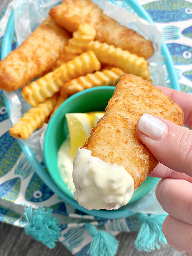 dipping air fryer frozen fish fillet into tartar sauce