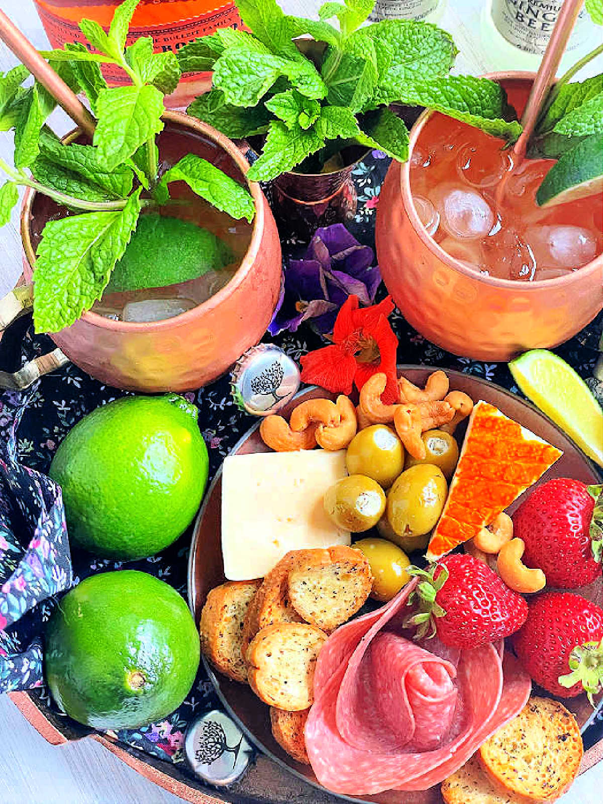 two copper mugs of bourbon mule pictured with a charcuterie board
