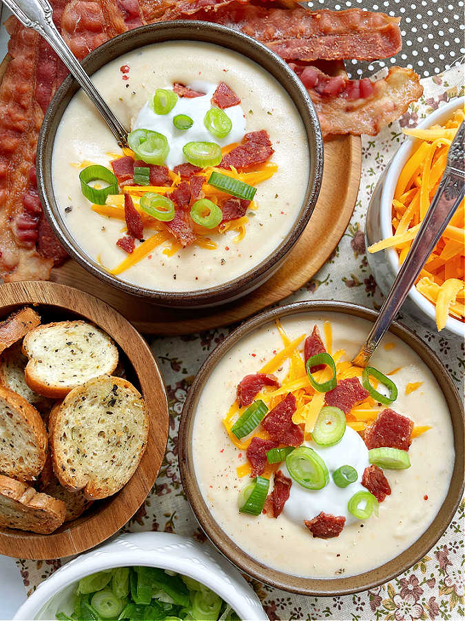 two bowls of crockpot potato soup with all the fixings