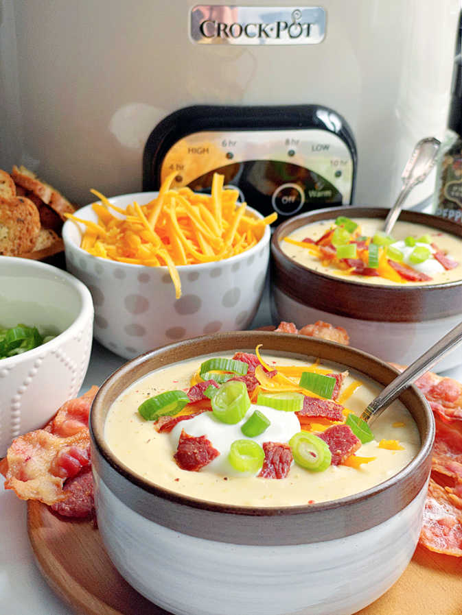 bowls of potato soup topped with garnish in front of the Crockpot