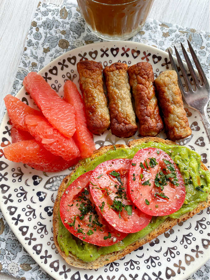 air fryer breakfast sausage plated with a slice of avocado toast and grapefruit slices