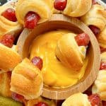 a platter full of air fryer pigs in a blanket with a small bowl of cheesy mustard sauce for dipping
