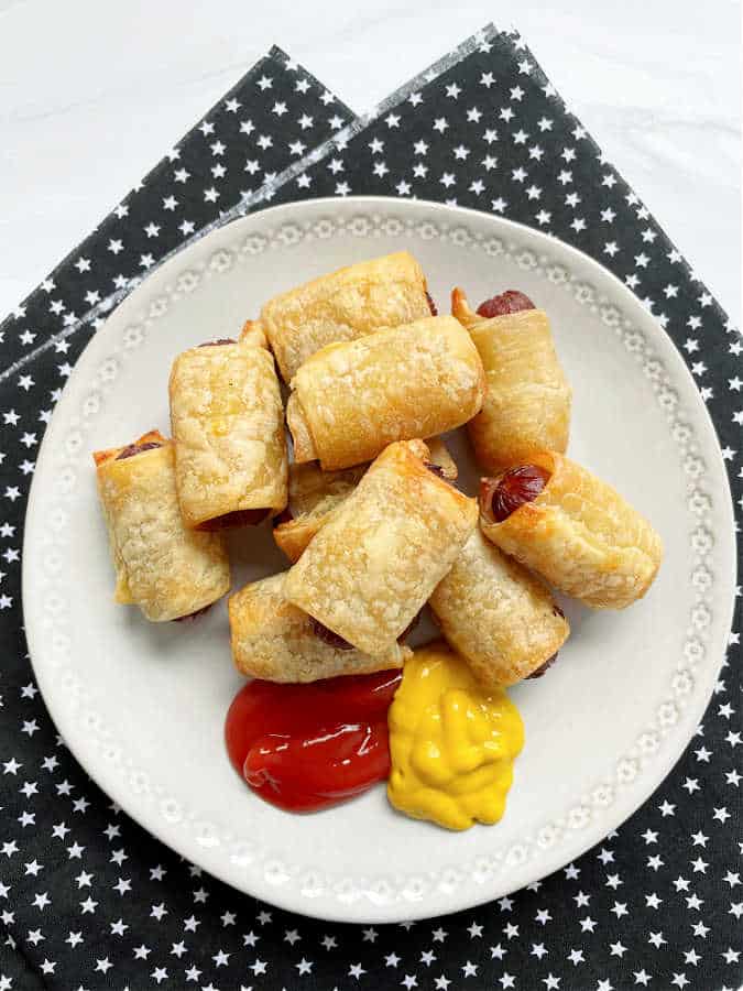 plated air fried from frozen pigs in a blanket, with ketchup and mustard for dipping