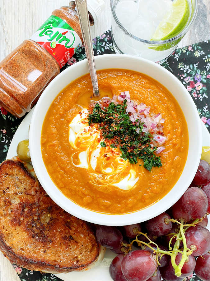 bowl of pumpkin soup, garnished and pictured with a jar of Tajin seasoning