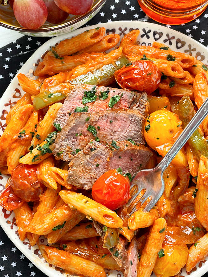 taking a bite of steak pasta