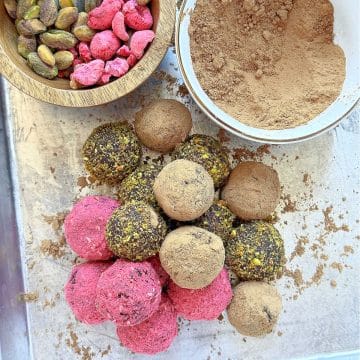 healthy chocolate truffles coated in freeze dried raspberries and pistachios on a tray
