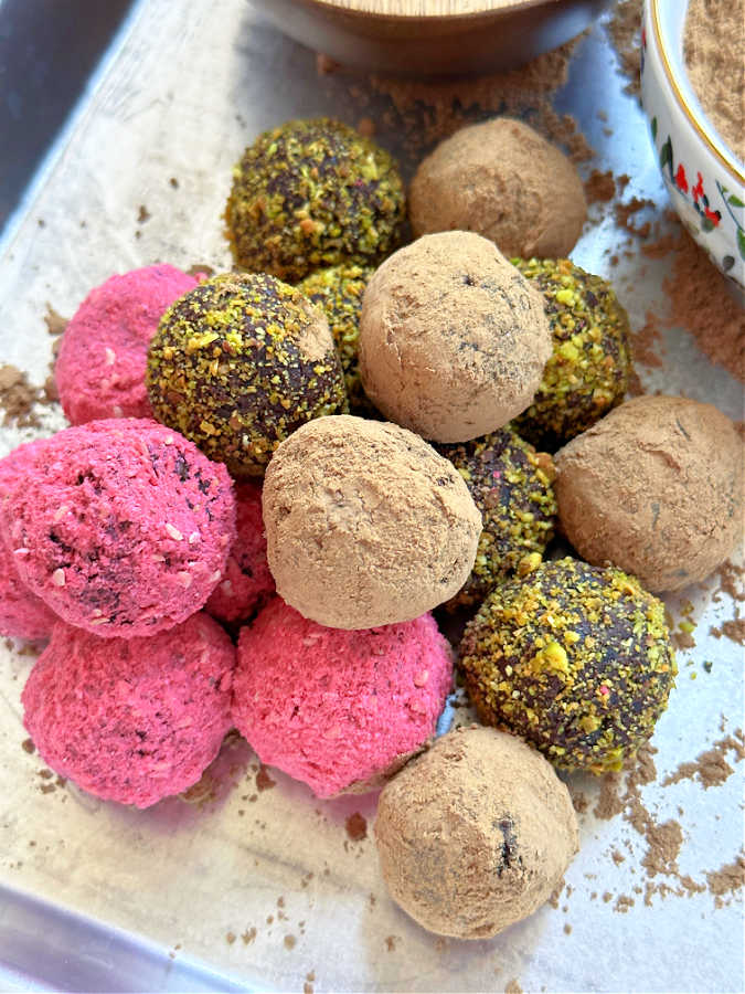 a pile of healthy chocolate truffles coated in freeze dried raspberries, pistachios and Cacao Bliss