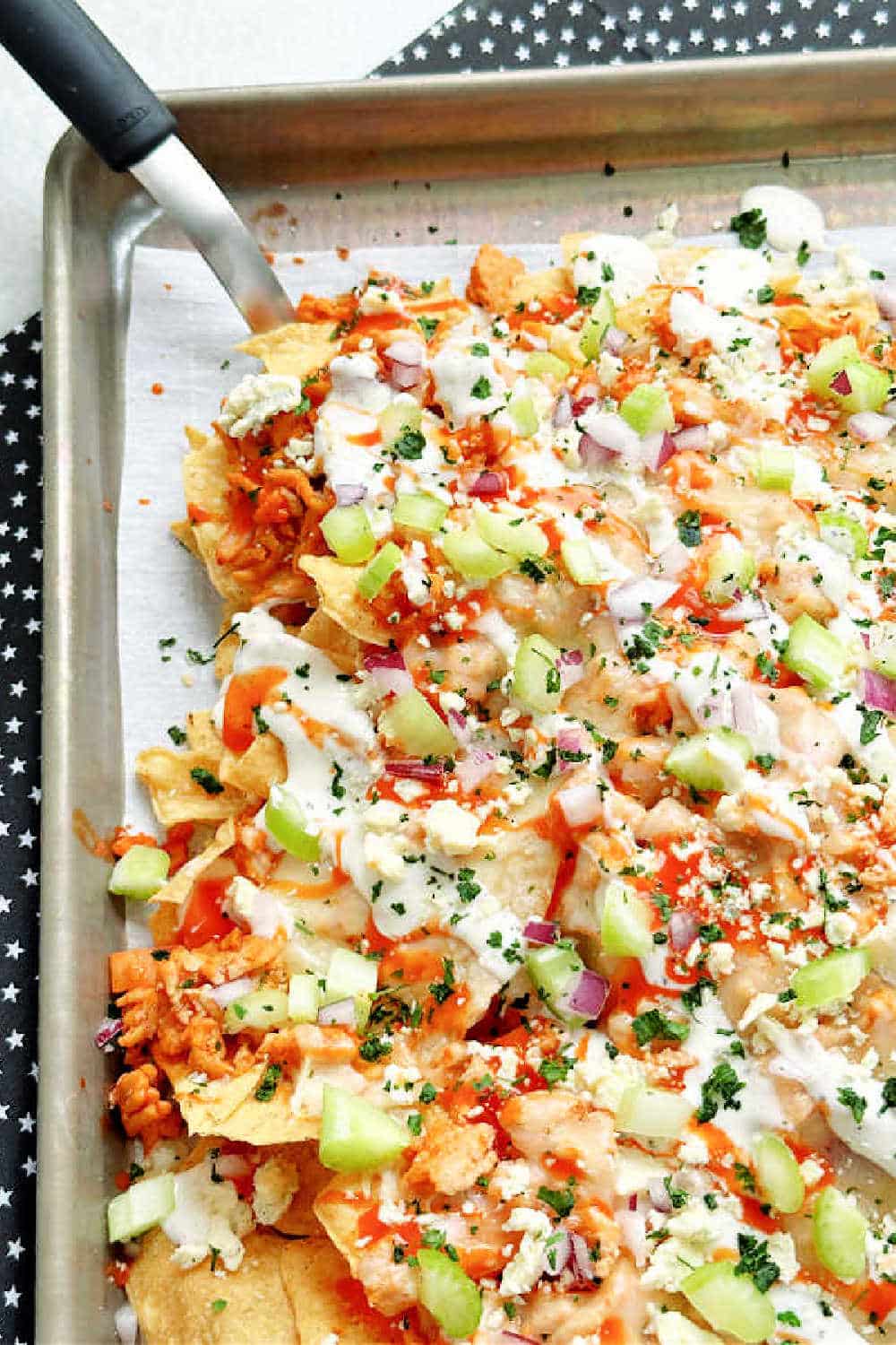 Learn how to make the perfect Buffalo Chicken Nachos with layers of buffalo chicken and lots of cheese all baked in the oven on a sheet pan. via @foodtasticmom